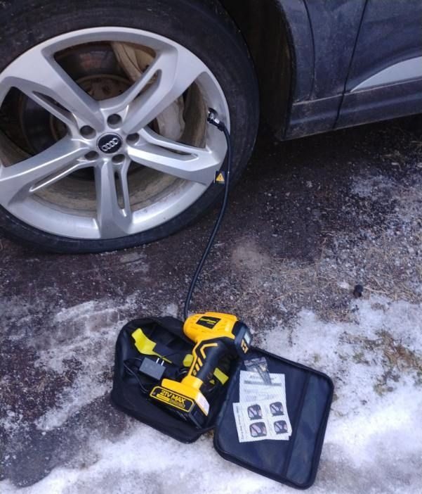 A cordless tire inflator and plug kit beside a car tire