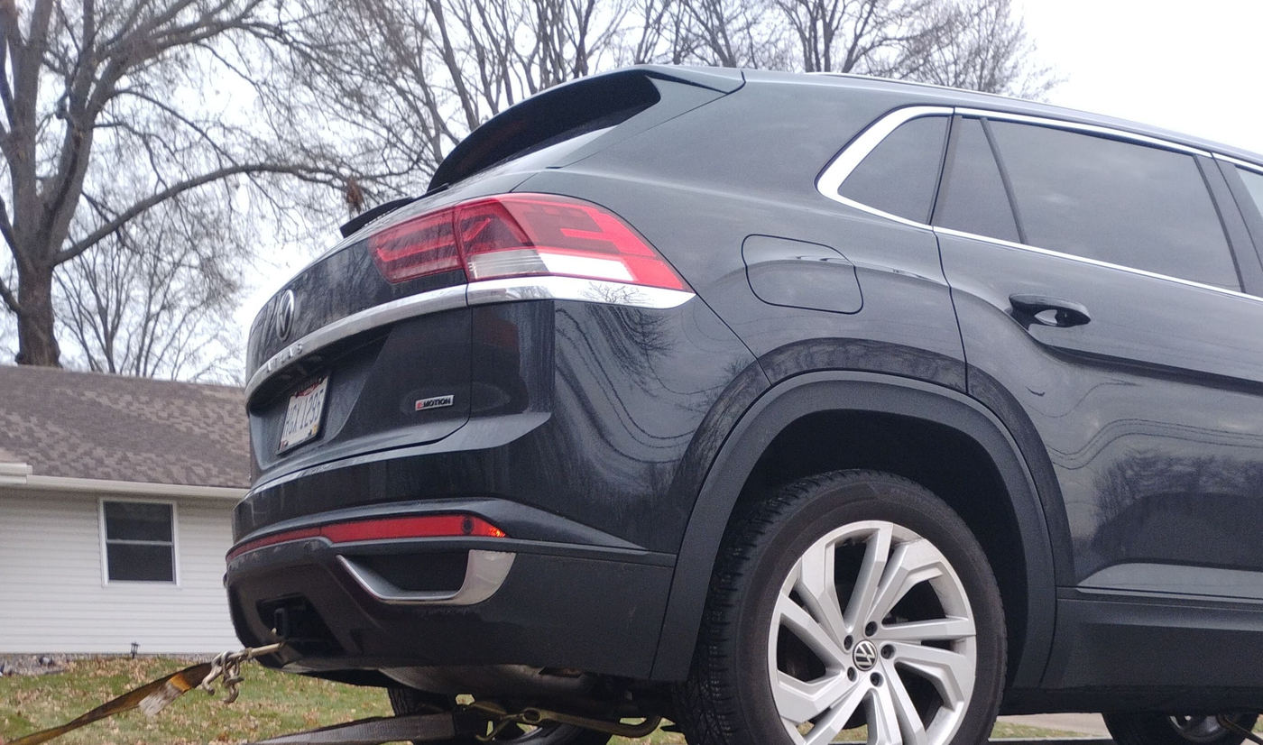 An all-wheel-drive SUV secured on the flatbed with a strap over the tire