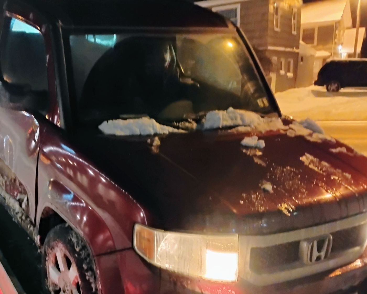 A snow-covered car sitting up on the flatbed deck at night